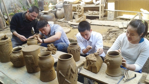 Họa sĩ Đào Ngọc Huỳnh (đeo kính) hướng dẫn các học sinh Trường Nguyễn Đình Chiểu làm gốm.