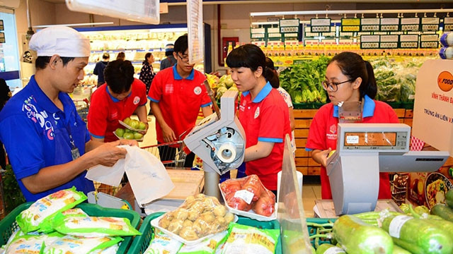 Các bạn trẻ được nhân viên siêu thị hướng dẫn cách đóng gói thực phẩm. Ảnh: HÙNG KHOA