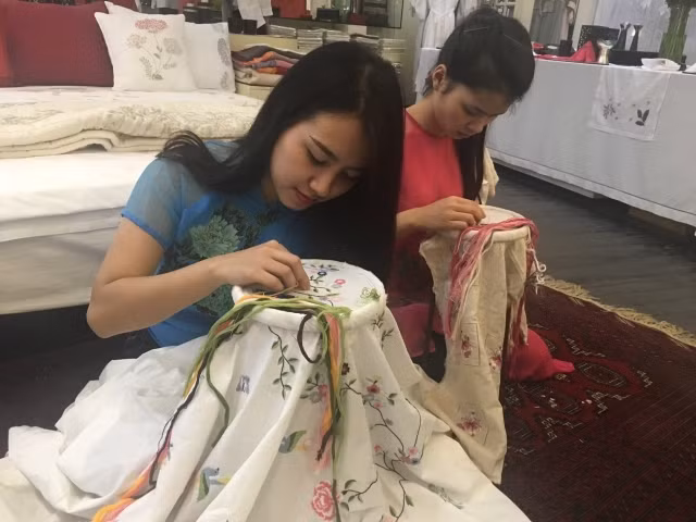 Các thợ thêu trẻ của Tân Mỹ Design thao tác trên vải.