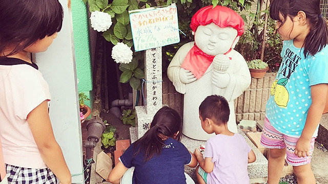 Các em nhỏ Nhật Bản đặt quà dưới bệ thờ thần Jizo. Ảnh: TWITTER