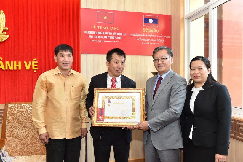 Đồng chí Thong Sa-vẳn Phôm-vi-hản, Đại sứ đặc mệnh toàn quyền nước CHDCND Lào tại Việt Nam trao tặng Huân chương cho gia đình Đại tá, bác sĩ Đặng Văn Tiến.