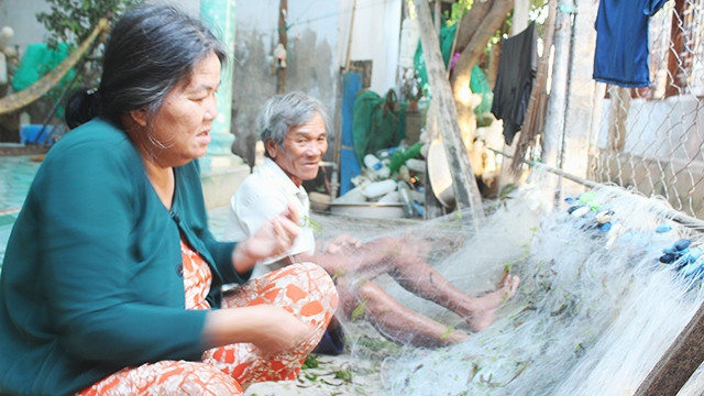 Hai vợ chồng già trong thôn gỡ rác trong lưới.