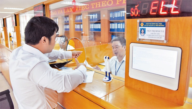 Giải quyết thủ tục hành chính cho người dân tại Bộ phận một cửa UBND quận Long Biên. Ảnh: MINH HÀ