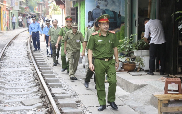 Lực lượng chức năng kiểm tra, nhắc nhở các cửa hàng kinh doanh tại khu vực đường tàu phố Phùng Hưng. (Ảnh: ĐĂNG ANH)