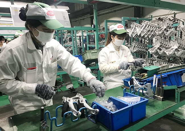 Công nhân Công ty TNHH sản xuất phụ tùng ô-tô và xe máy Việt Nam (Hưng Yên) trong ngày làm việc đầu tiên sau kỳ nghỉ Tết Nguyên đán.