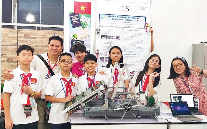 Anh Dương Trung Hiếu và nhóm học sinh Trường THCS Ngô Sĩ Liên (quận Hoàn Kiếm) bên mô hình thuyền vớt rác trên sông.