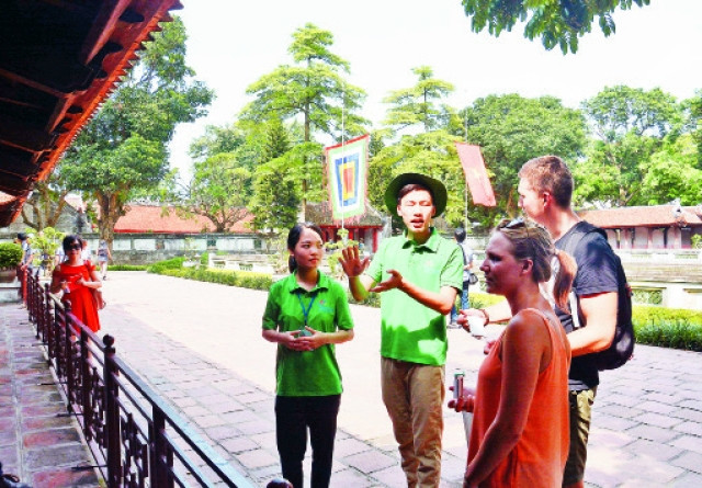 Tình nguyện viên du lịch hướng dẫn cho du khách nước ngoài về di tích lịch sử Văn Miếu - Quốc Tử Giám.Ảnh: MINH HÀ