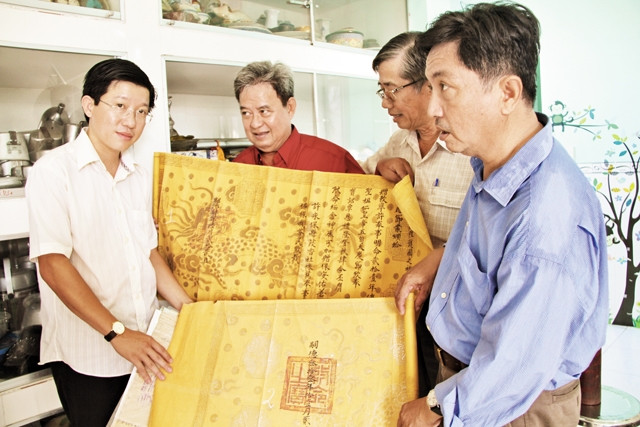 Nhà giáo Ưu tú, nhà sưu tập Lê Phùng Xuân (giữa) giới thiệu một bản sắc phong triều Nguyễn.  