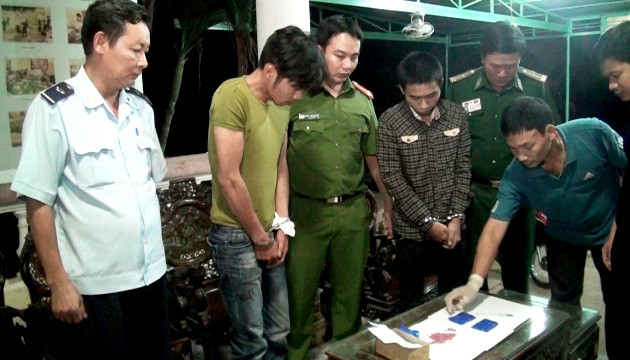 Trần Minh Tâm (thứ hai từ trái qua) và Lương Thanh Hoàng (thứ tư từ trái qua) cùng tang vật tại cơ quan điều tra.