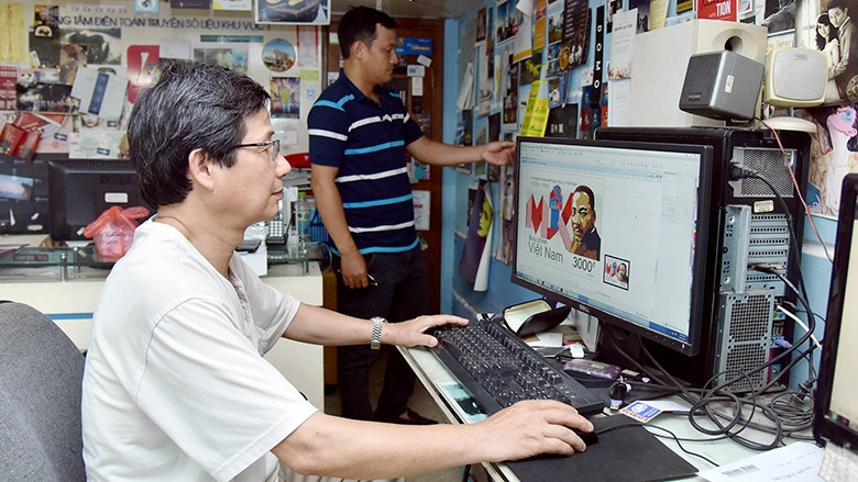 Họa sĩ Trần Vinh đang hoàn tất một mẫu tem mới. Ảnh: NGUYỄN ÐĂNG