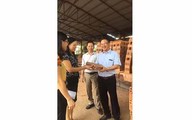 Đồng chí Nguyễn Văn Quyền, Bí thư Chi bộ, Giám đốc Công ty TNHH Xây dựng Xuân Quyền (người đầu tiên bên phải) giới thiệu sản phẩm gạch tuy-nen của công ty.