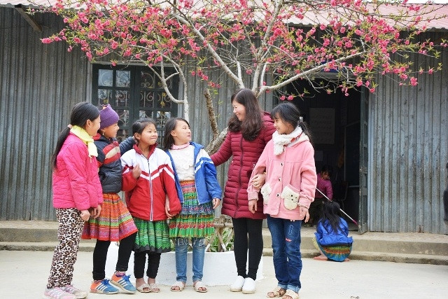 Cô và trò Trường dân tộc nội trú xã Phình Hồ bên gốc đào xuân trong khuôn viên nhà trường. (Ảnh: THANH SƠN)