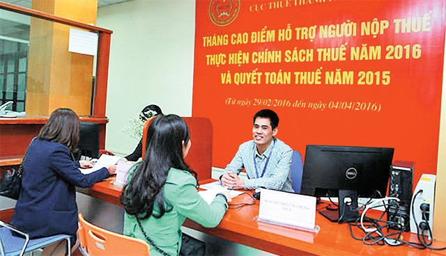 Cán bộ Cục Thuế Hà Nội giải đáp vướng mắc của người dân tại bàn hỗ trợ chính sách thuế.      Ảnh: KIM LIÊN