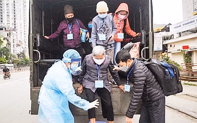 Cán bộ y tế phường Ðồng Tâm đón các bệnh nhân "xóm chạy thận" trên phố Lê Thanh Nghị ra xe ô-tô chở đến BV Bạch Mai khám bệnh.