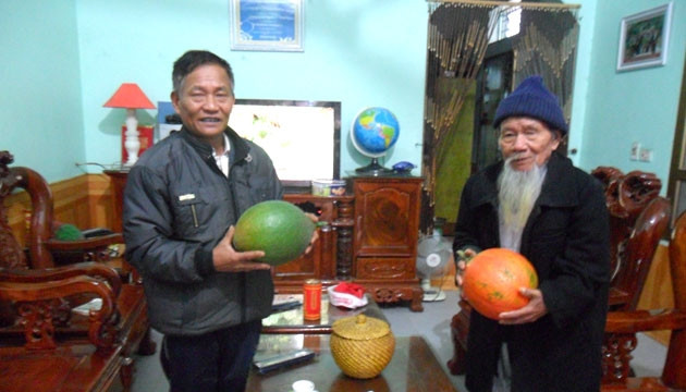 Ông Trần Sĩ Quảng (bên trái) với quả gấc nặng 5 kg.