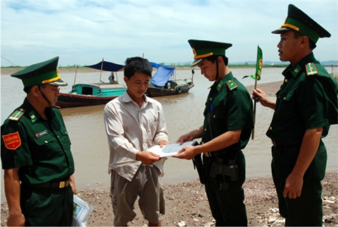 Cán bộ, chiến sĩ Ðồn Biên phòng Kim Sơn (Ninh Bình) phổ biến pháp luật cho ngư dân.   Ảnh: HỒNG VÂN