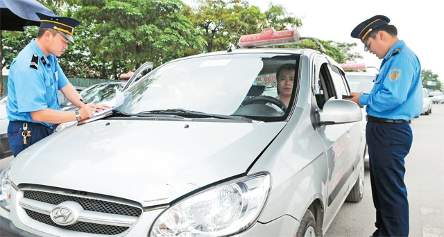 Thanh tra giao thông kiểm tra giấy tờ xe ta-xi trước khi xuất bến tại Bến xe Mỹ Đình. Ảnh: THANH HẢI