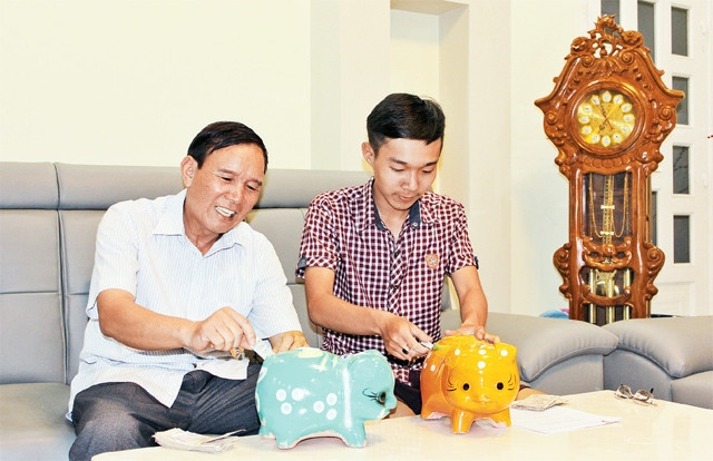 Ông Nguyễn Ngọc Tương và con trai bỏ tiền vào heo đất.