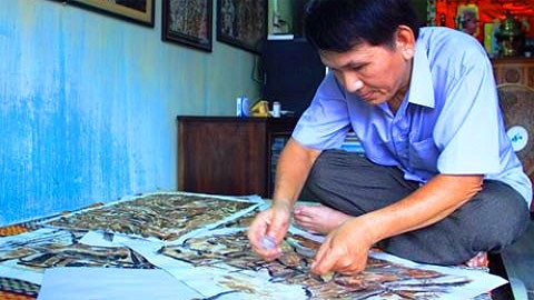 Nghệ nhân Đinh Ngọc Đạt đang hoàn thiện một tác phẩm về phố cổ Hội An.