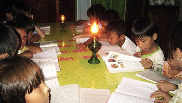 Những đứa trẻ ở ấp Mỹ Thạnh hàng đêm vẫn phải đánh vật với con chữ dưới ánh đèn dầu tù mù. (Ảnh: congan.com.vn)