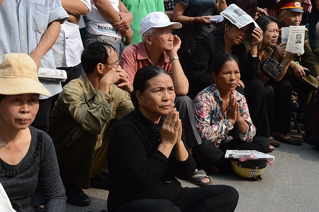 Nhiều người ngồi trong vườn hoa góc đường Trần Hưng Đạo- Lê Thánh Tông để theo dõi tang lễ Đại tướng Võ Nguyên Giáp. (ảnh: Linh Phan)