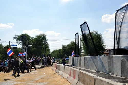 Người biểu tình dùng dây dỡ hàng rào bê-tông chặn đường đến Phủ Thủ tướng ở Thủ đô Băng-cốc, Thái-lan. Ảnh: TRƯỜNG SƠN