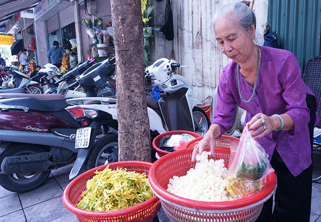 Bà Phan Thị Thu bên gánh hàng hoa trên phố Hàng Khoai. Ảnh: LÊ BÍCH