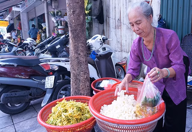 Bà Phan Thị Thu bên gánh hàng hoa trên phố Hàng Khoai. Ảnh: LÊ BÍCH