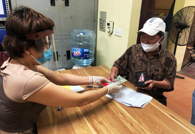 Cán bộ phường Ô Chợ Dừa, quận Đống Đa chi trả tiền hỗ trợ cho người dân.