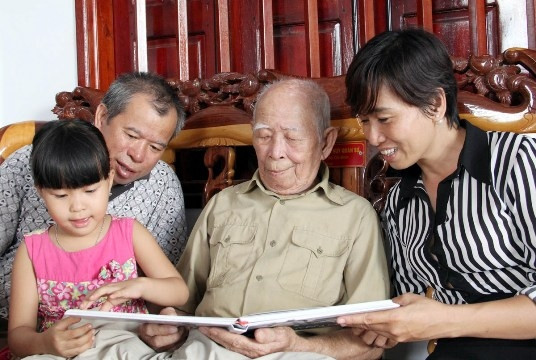 Cụ Tô Đình Cắm cùng con cháu xem những hình ảnh về Đội Việt Nam Tuyên truyền Giải phóng quân. 