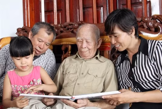 Cụ Tô Đình Cắm cùng con cháu xem những hình ảnh về Đội Việt Nam Tuyên truyền Giải phóng quân. 