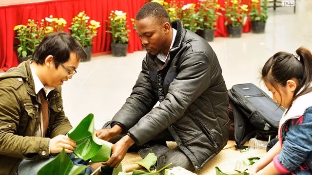 Du khách quốc tế tham gia trải nghiệm gói bánh chưng. Ảnh: THANH TÚ
