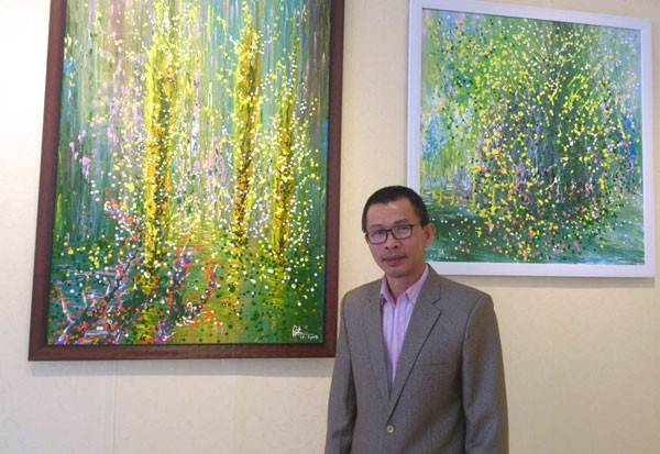 Họa sĩ Võ Trịnh Biện bên tác phẩm triển lãm.