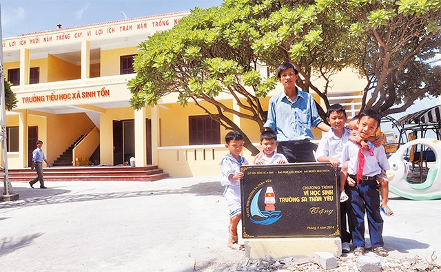 Thầy giáo và học sinh Trường tiểu học xã Sinh Tồn bên ngôi trường mới. Ảnh: LONG THÀNH