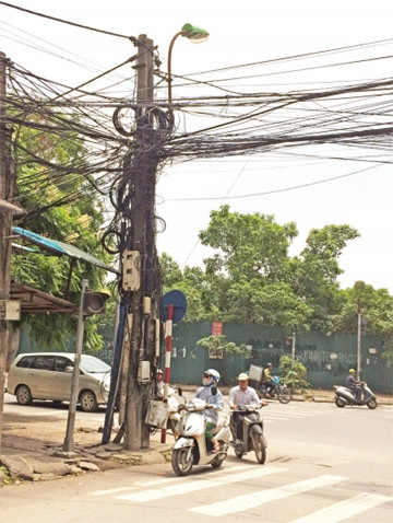 Hàng búi dây cáp các loại treo lơ lửng trên phố Đào Duy Anh làm xấu cảnh quan và gây nguy hiểm cho người đi đường.