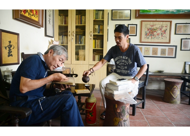 Nhà sưu tập Nguyễn Thế Bách (bên phải) trao đổi về sách với bạn bè.