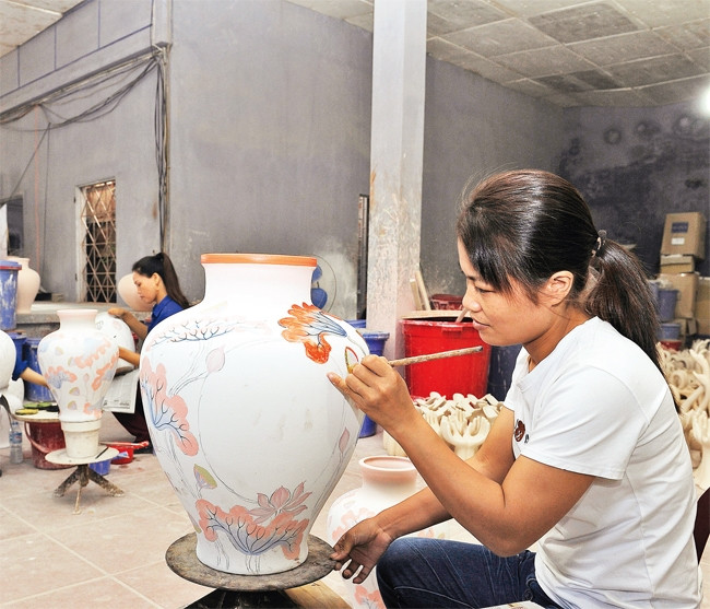 Vẽ hoa văn lên sản phẩm gốm Bát Tràng. Ảnh: HÀ THU