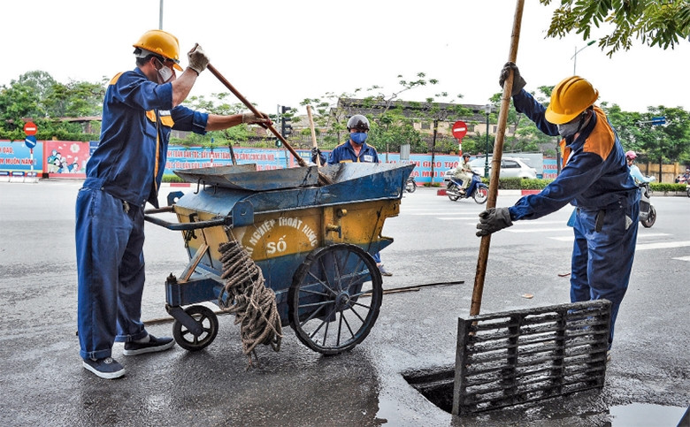 Công nhân Xí nghiệp thoát nước số 5 nạo vét cống ngầm, bảo đảm tiêu thoát nước trong mùa mưa bão trên tuyến đường Nguyễn Văn Cừ. Ảnh: ĐĂNG ANH