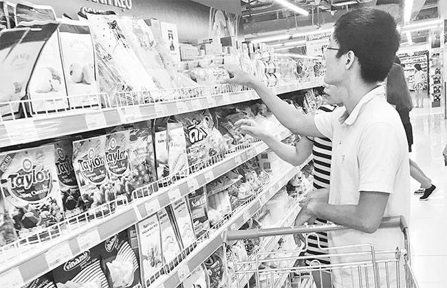 Người tiêu dùng chọn mua bánh kẹo tại siêu thị VinMart (Hà Nội).
