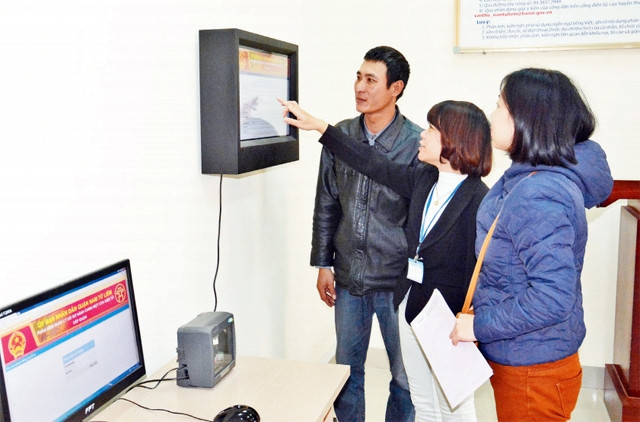 Cán bộ tại Bộ phận một cửa UBND quận Nam Từ Liêm hướng dẫn người dân tra cứu phần mềm quản lý hồ sơ điện tử. Ảnh: DUY LINH