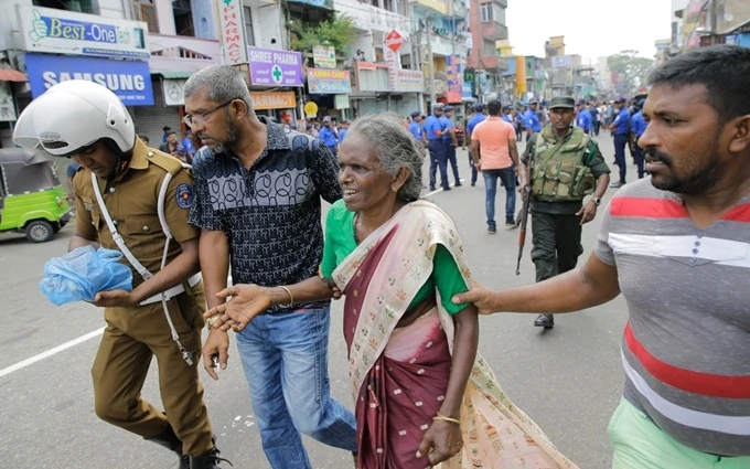 Người phụ nữ Sri Lanka nhận được sự giúp đỡ bên ngoài Đền thờ Thánh Anthony sau vụ nổ ngày 21-4. (Ảnh: AP)