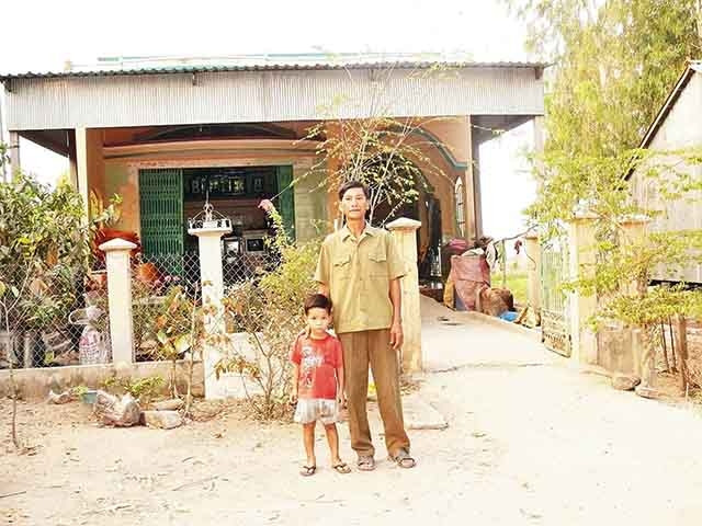 Ông Ba Long cùng cháu nội trước căn nhà mới. 