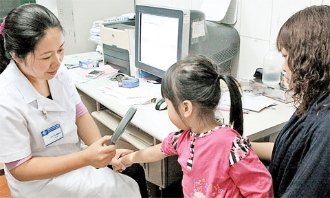 Bác sĩ khám bệnh cho trẻ bị viêm da do tiếp xúc với côn trùng tại Bệnh viện Da liễu Hà Nội. Ảnh: DƯƠNG NGỌC 