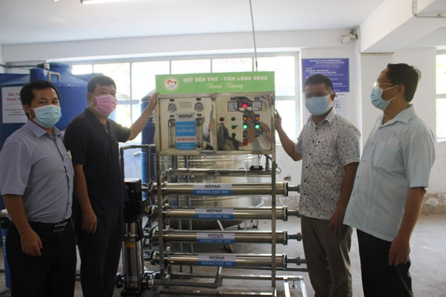 Lãnh đạo chính quyền địa phương tiếp nhận máy lọc nước mặn thành nước ngọt từ đơn vị tài trợ.