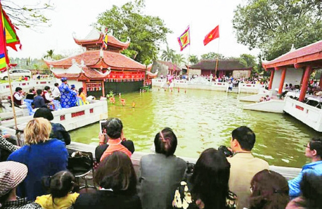 Khán giả xem múa rối nước tại thủy đình làng Đào Thục, huyện Đông Anh. Ảnh: KHÁNH LAN