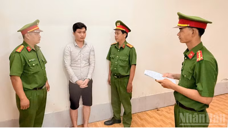 Điều tra viên thi hành lệnh bắt bị can để tạm giam đối với Huỳnh Thanh Huy. (Ảnh: Công an cung cấp)