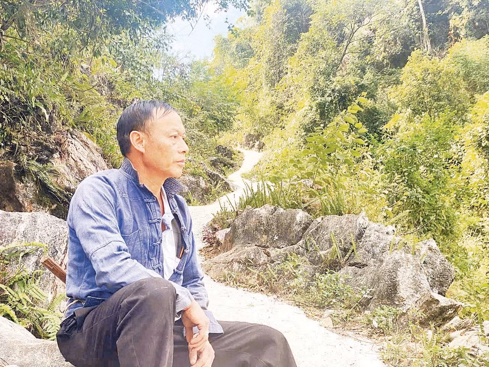 Bí thư Chi bộ Thào A Quả bên một đoạn đường anh đã vận động bà con chung sức hoàn thành. Ảnh: Doãn Hoàng 