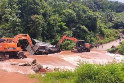 Kéo xe bị nghiêng do nước lũ vào nơi an toàn. (Ảnh: BIÊN CƯƠNG)