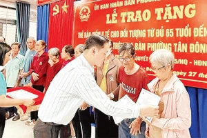 Trao thẻ Bảo hiểm y tế cho người cao tuổi phường Tân Đông Hiệp. (Ảnh: VÕ LÊ)