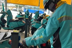 Các lái xe công nghệ bằng xe điện hai bánh sạc pin tại một cơ sở cung cấp dịch vụ sạc pin. 